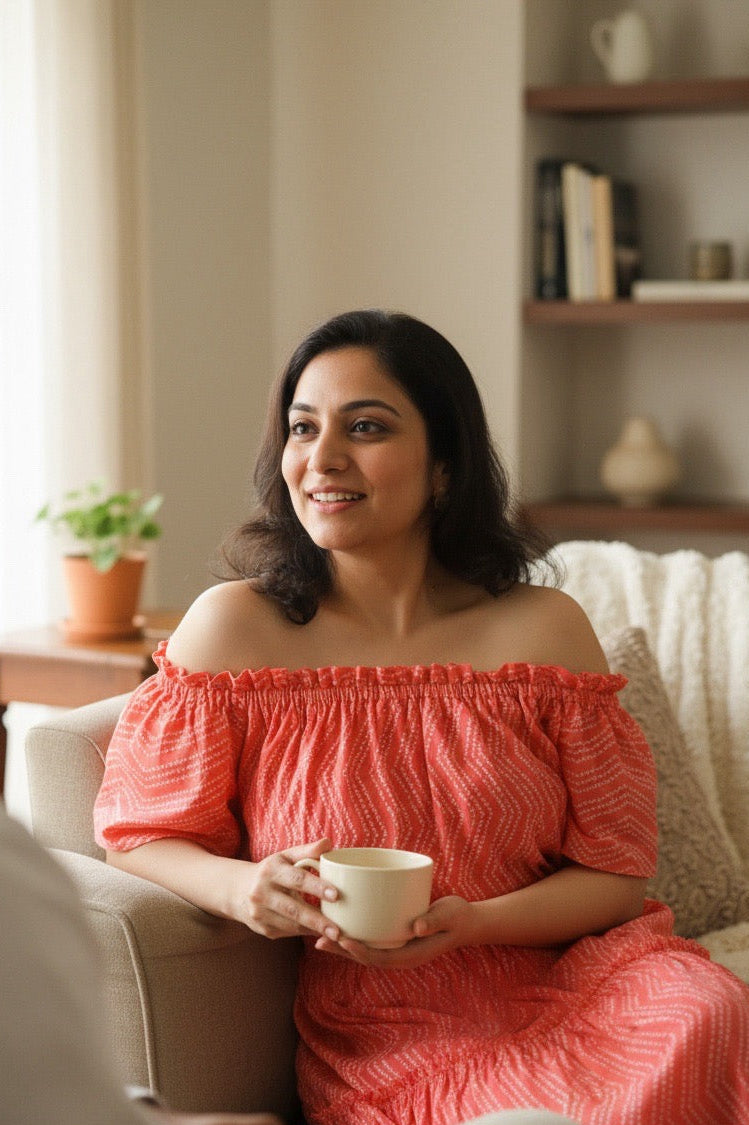 Woman in a pink dress holding a cup in a cozy living room.