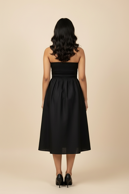 Woman wearing a black strapless dress against a beige background