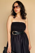 Woman wearing Blue Hour Black Linen Strapless Midi Dress with a belt against a beige background