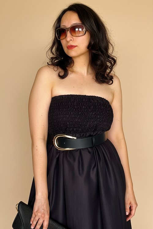 Woman wearing Blue Hour Black Linen Strapless Midi Dress with a belt against a beige background