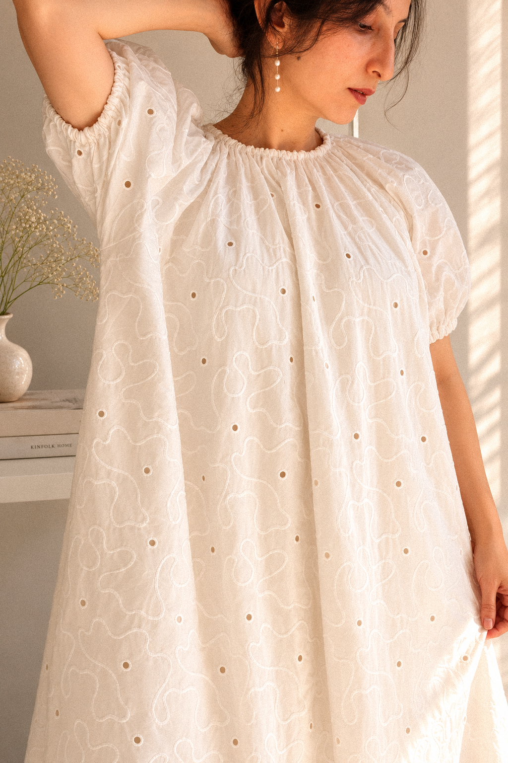 Close up of woman in Cloudline White Eyelet Cotton Maxi Dress With Puff Sleeve, showing the pattern and cutwork, gathered neck and elastic sleeves.