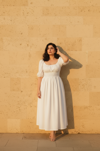 Woman in a white dress standing against a beige wall