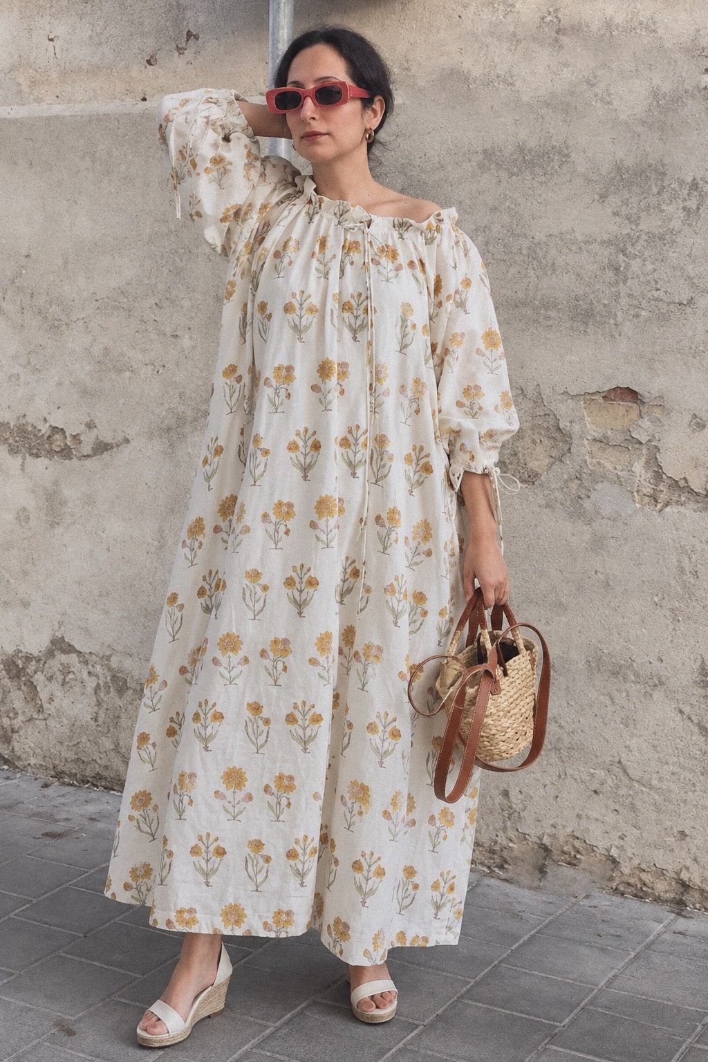 Woman wearing daydream cream floral cotton maxi dress with cream base and small yellow flower all over. dress has neck tie and ties around the cuffs for ease of wearing. 