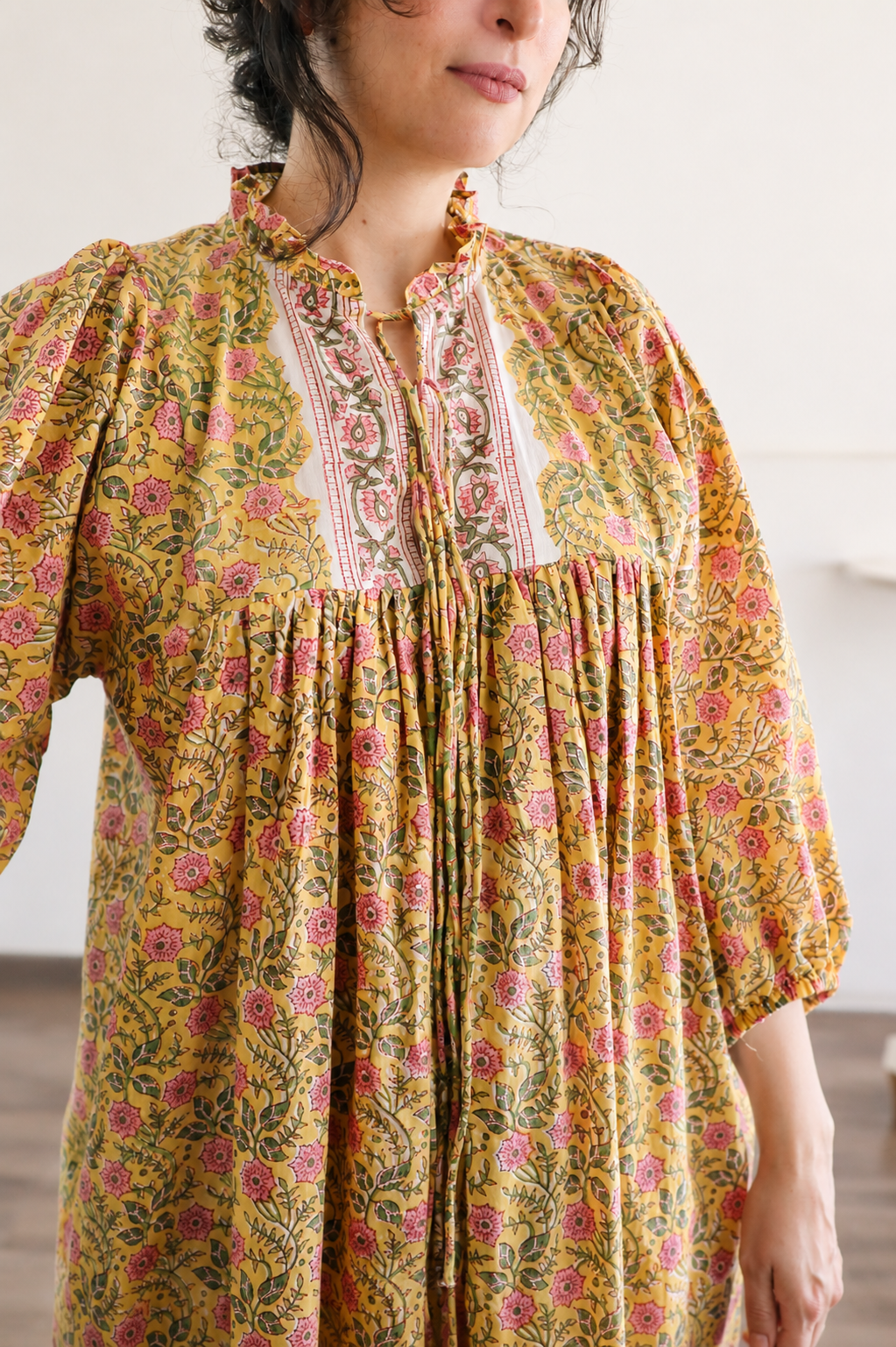 Woman wearing Evening Blush Midi Dress in Mustard Floral Handblock Sanganeri Cotton. Showcasing Neck Ties Details.