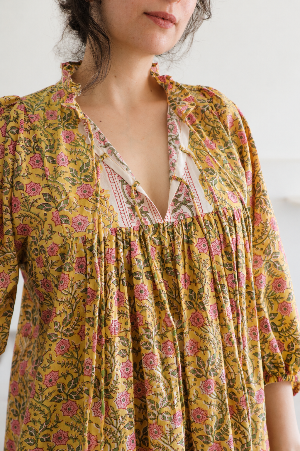 Woman wearing Evening Blush Midi Dress in Mustard Floral Handblock Sanganeri Cotton. Showcasing Neck Ties Details.