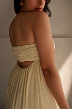 Woman wearing Golden Hour Buttercream Yellow Strapless Vacation Maxi Dress, Closeup of the shirred elastic back and the cutout design.