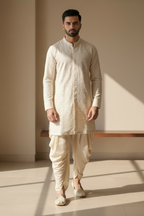 Man wearing a traditional cream kurta with white pants in a minimalistic setting