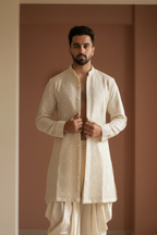 Man wearing a traditional cream kurta with a plain background