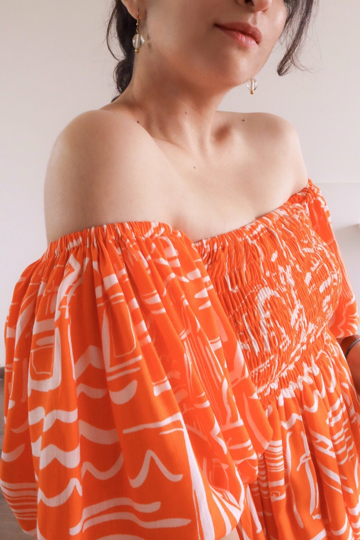 Woman wearing Sea Star Tangerine/Orange Mulmul Cotton Puff Sleeve Midi Dress, Closeup shot against a neutral background