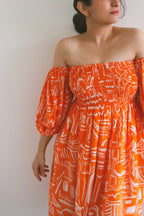 Woman wearing Sea Star Tangerine/Orange Mulmul Cotton Puff Sleeve Midi Dress against a plain background