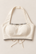 An off-white halter crop top with a decorative band of silver mirror work across the neckline and a matching silver embroidered trim along the bottom edge and drawstrings.