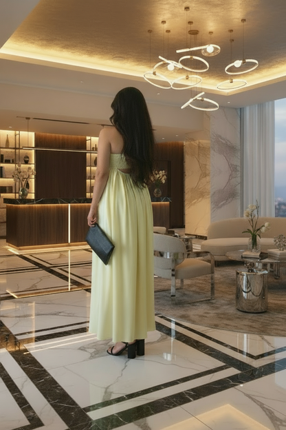 Woman in a yellow dress standing in a luxurious lobby with marble floors and modern decor.