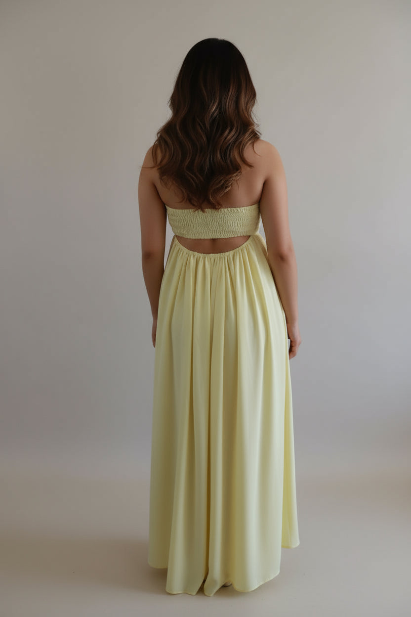 Model wearing Golden Hour Buttercream Yellow Strapless Vacation Maxi Dress, showing smocked back detail and cutout.